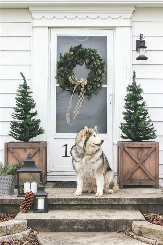 Ön kapının iki yanında iki çalı ve kapıda tek boynuz bulunan bir Noel dekorasyonu