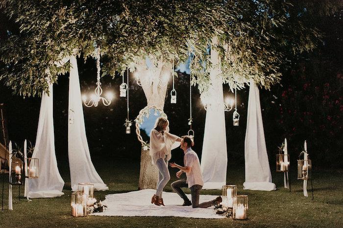 ideja o romantični poroki na travniku v gozdu, dekoracija zrcala, bele tančice, luči s svečami, elegantni lestenci