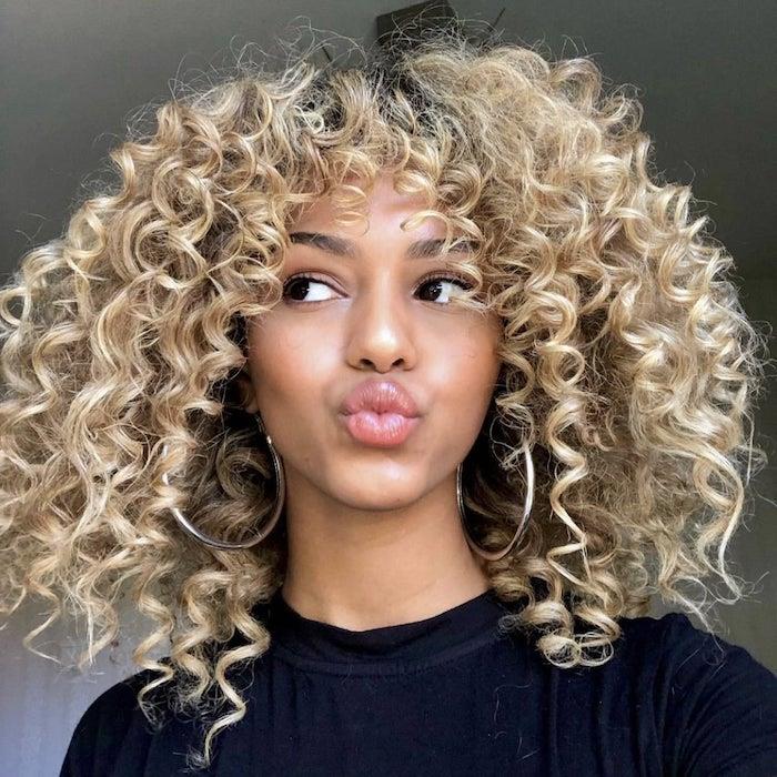 kulaklarında büyük halkalar ve saçak saç modeli kıvırcık saçlı afro bir kadın