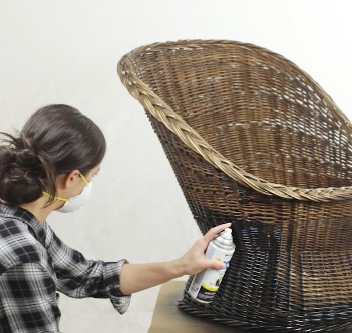 moteris su kauke dažo rotango kėdę purškiamais dažais