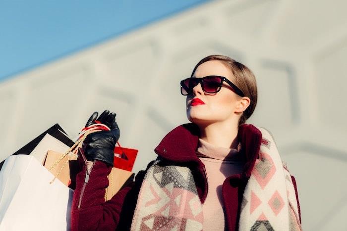 ženska z nakupovalnimi torbami za sončna očala z rdečimi šminkami