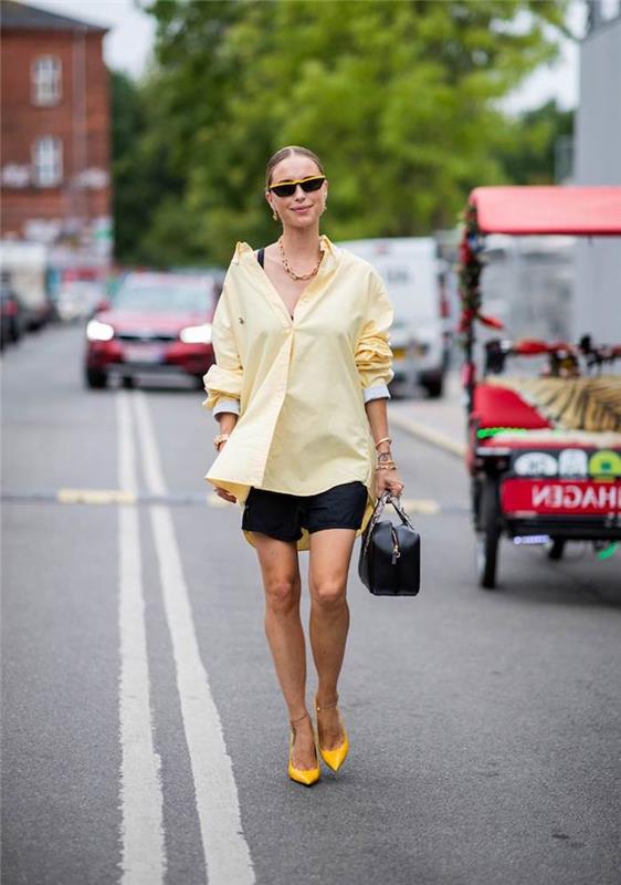 ženska na ulici z rumeno bluzo in kratkimi hlačami v modnih barvah