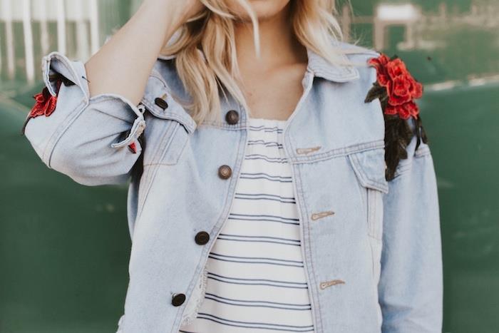 ženska v belem črtastem topu in denim jakni po meri z vezenim cvetjem na rami