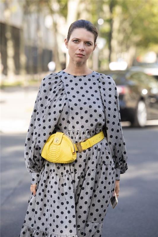 ženska, oblečena v sivo obleko s pikami in rumeno torbico pantone 2021