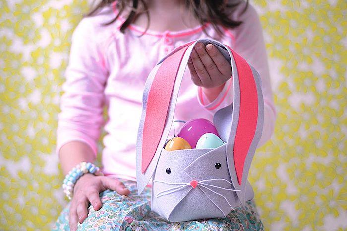 plastik yumurtalarla dolu bir tavşan şeklinde kolay bir Paskalya sepeti dekorasyonu tutan bir kız