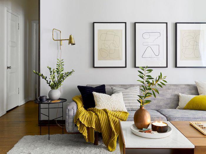 dnevna soba s sivim kavčem in rumeno odejo slik na stenah barvni trend deco 2021