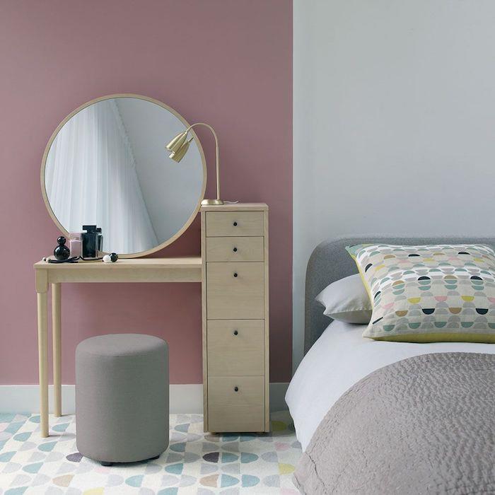 stolček pred lesenim straniščem z okroglim ogledalom v sivi in ​​rožnati spalnici