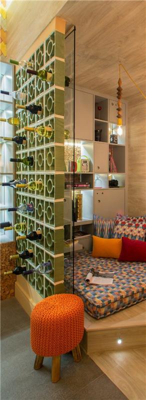 predelna stena s krožnimi posodami za vinske steklenice, delilec prostora v zeleni barvi reseda za razmejitev spalnice