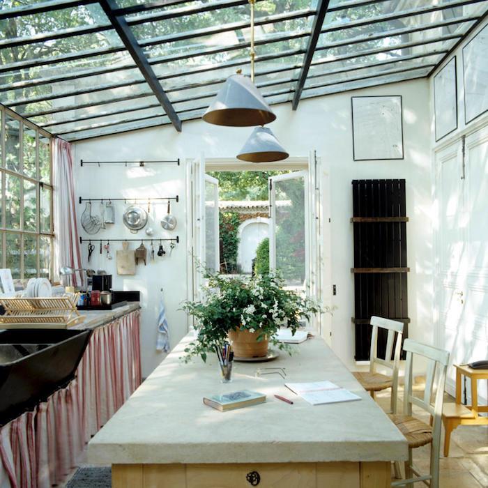 veranda pod pergolo, opremljena v kmečkem slogu in ni pretenciozna z visečimi svetilkami in cvetličnim loncem pri mizi