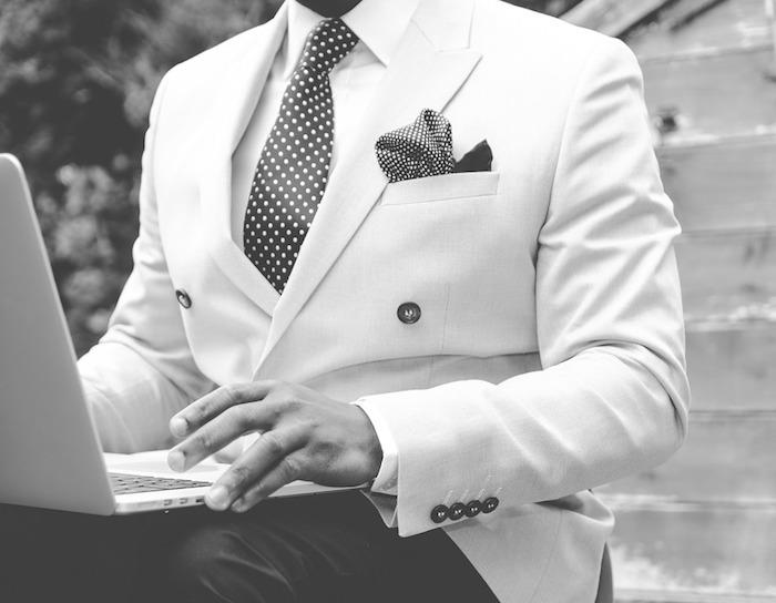 elegantna moška obleka v obleki z belim suknjičem, belo srajco in črno kravato, črne hlače