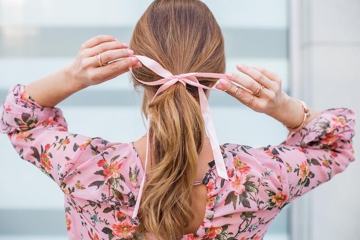 z trakom za vezavo las ima ženska v rožnati majici rože z lasmi v čop