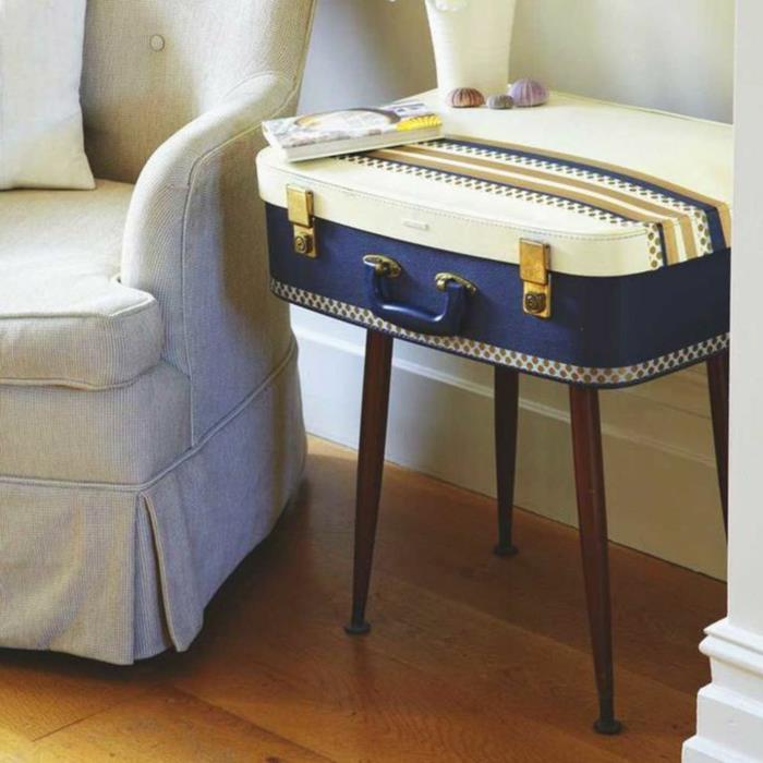 gražus lagaminas, naudojamas kaip dizainerio naktinis stalas, pilkas fotelis, medinės grindys