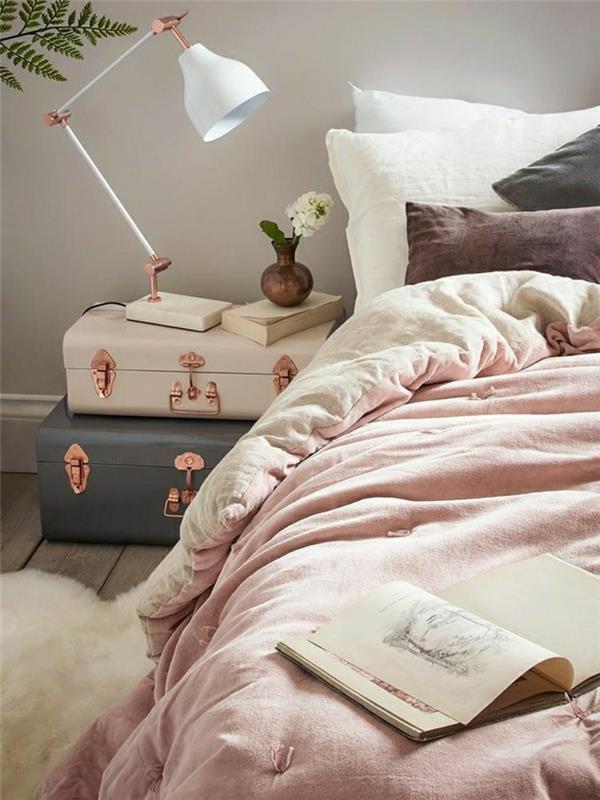 rausvos ir pilkos spalvos miegamasis, balta stalinė lempa, senovinių švelnių spalvų lagaminai, rožinė antklodė