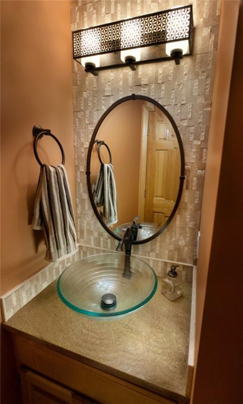 Banyoda fantastik aydınlatmalı cam lavabo ve oval ayna