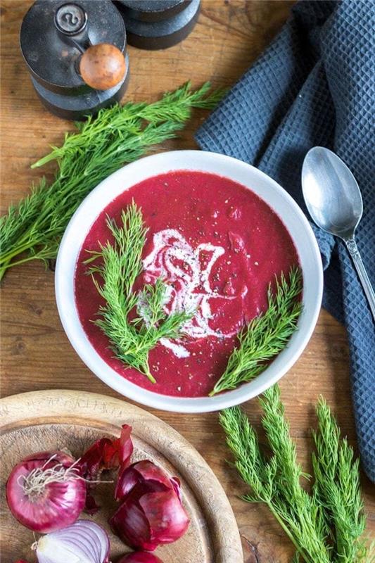 Vellutate invernali, minestra frullata di pomodoro e cipolla, piatto guarnito con erbette fresche