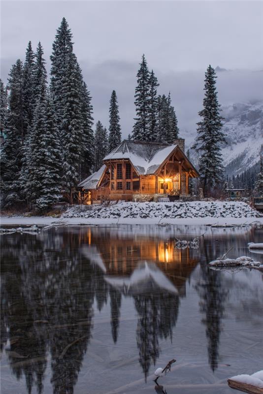 karlı bir ormanda güzel kış manzarası, dağlarda bir göl kenarında ahşap evin fotoğrafı