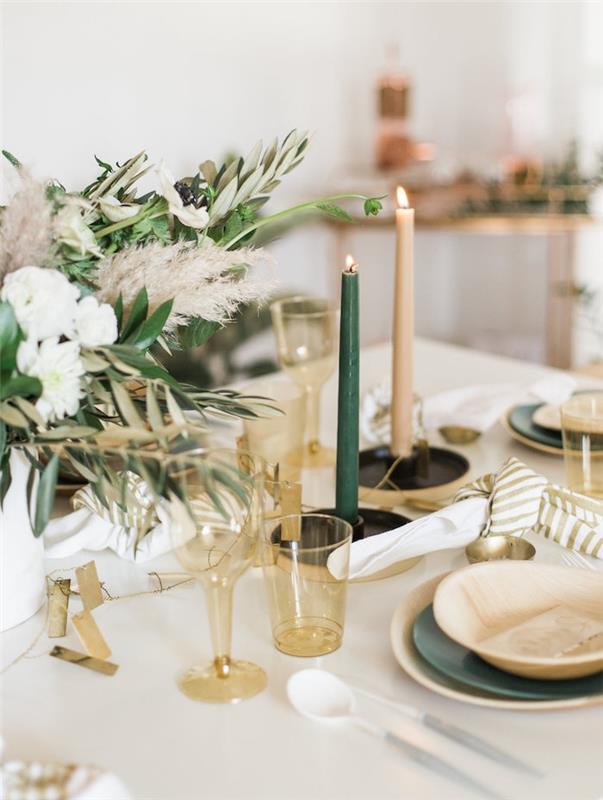 plastik bardaklı bitkisel dekor, beyaz masa örtüsü üzerinde yeşil ve kirli beyaz mumlar, çeşitli renklerde tabaklar