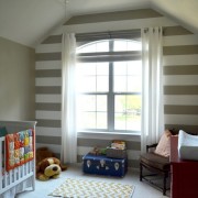 Uma parede do quarto das crianças é decorada com largas listras horizontais