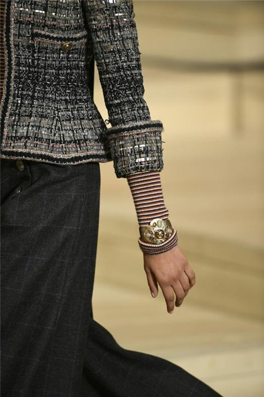 siva, črno -bela jakna iz Chanela, s sivim krilom, zloženimi rokavi, ki razkrivajo rokave z rdečimi in belimi črtami, elegantno spodnje udarno dno