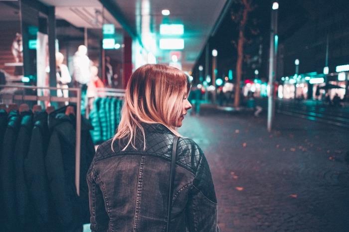 ženska frizura z blond tehniko ombré, barvanje na rjavi podlagi, model usnjene jakne in temna tkanina