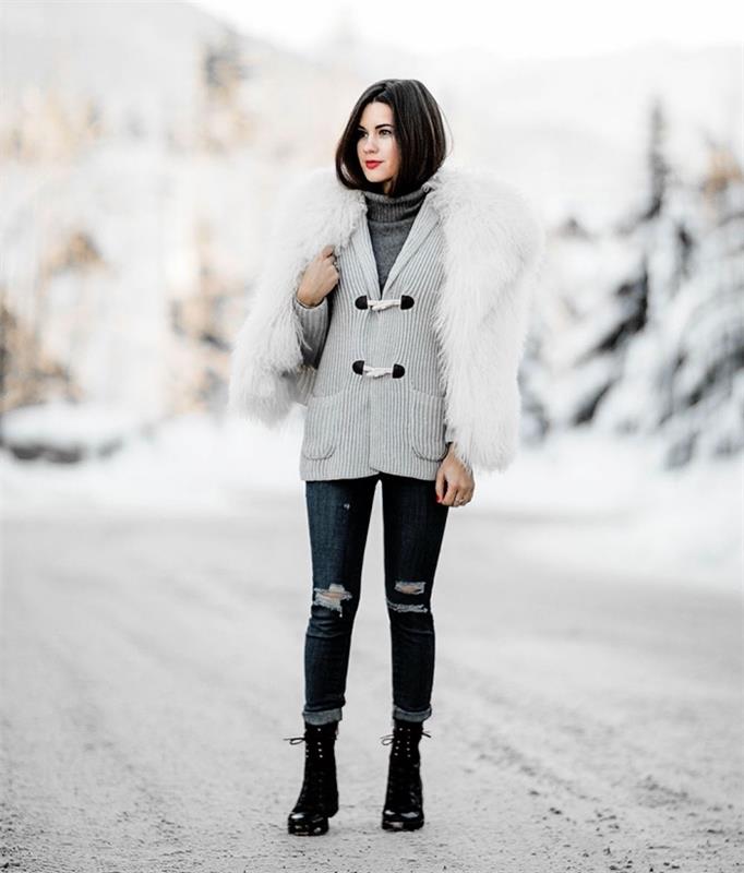 žiemos apranga, tamsiai suplėšytų džinsų modelis, dėvimas su liemene ir pilku megztiniu, batai su kulkšnimis su raišteliais ir baltu dirbtiniu kailiu