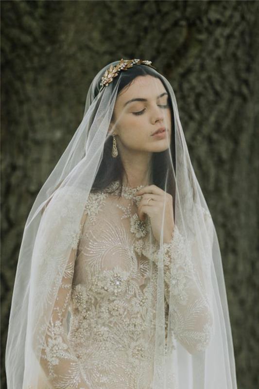 elegantiška nėrinių suknelė ilgomis rankovėmis kartu su ilga šydu ir žalvariniu vestuvių plaukų aksesuaru