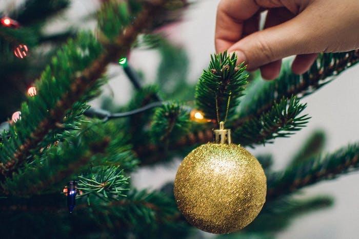 Kalėdų fonas žalioje Kalėdų eglutėje su aukso spindesiu kalėdiniu kamuoliu, lengva girlianda