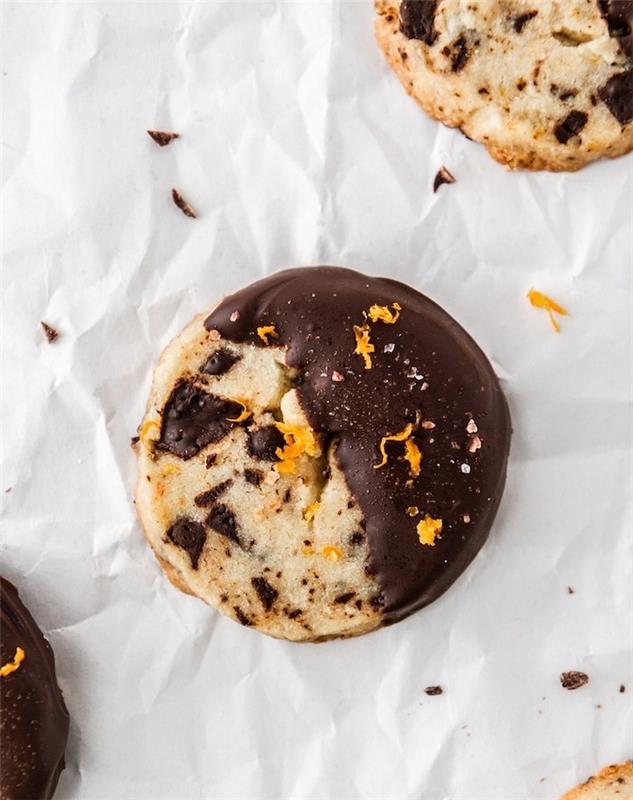sausainis, įmerktas į šokoladą, apelsino žievelė ant viršaus, naminis šokolado sausainių receptas, baltas kepimo popierius