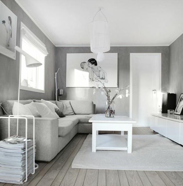 pilkos sienos, baltas medinis žurnalinis staliukas, pilka kampinė sofa, medinės grindys, kabančios nuotraukos, pilkos spalvos