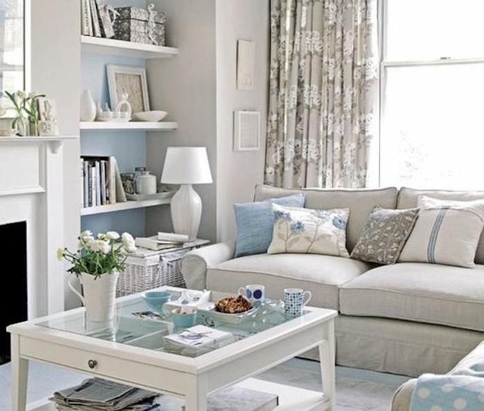 pilka sofa, mėlynai atspausdintos mesti pagalvės, pilkos spalvos, stiklo žurnalinis staliukas, pakabinamos lentynos