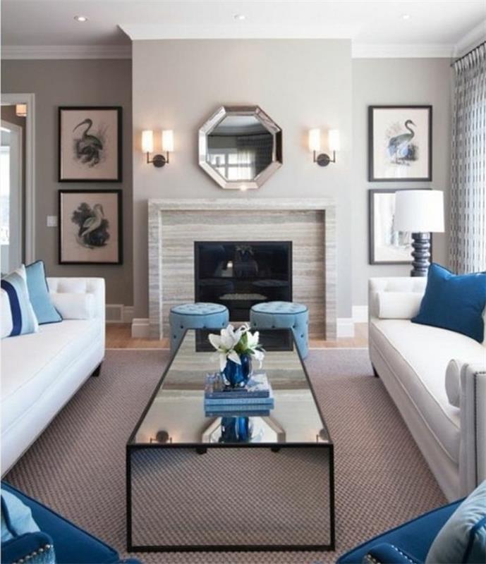 baltos sofos, mėlynai atspausdintos mesti pagalvės, mėlyni pufai ir foteliai, pilki svetainės baldai, stiklinis kavos staliukas