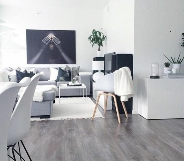 gražios svetainės, pilka kampinė sofa, spausdintos pagalvės, medinės grindys, balto metalo kavos staliukas