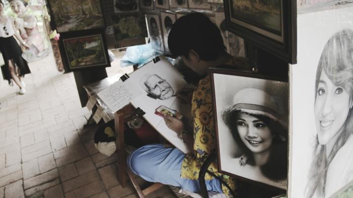 ženska, ki sedi na stolu in riše sliko, obkrožena z risbami, kako enostavno narisati dekle