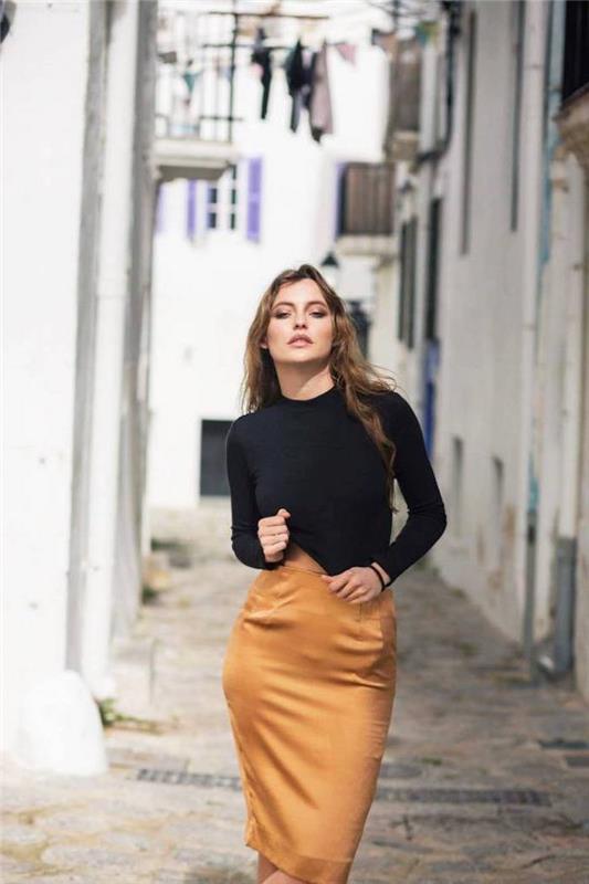 ženska, ki stoji na ulici, nosi rjavo svileno krilo in črno bluzo, trendi oblačil 2019, dolgi rjavi lasje