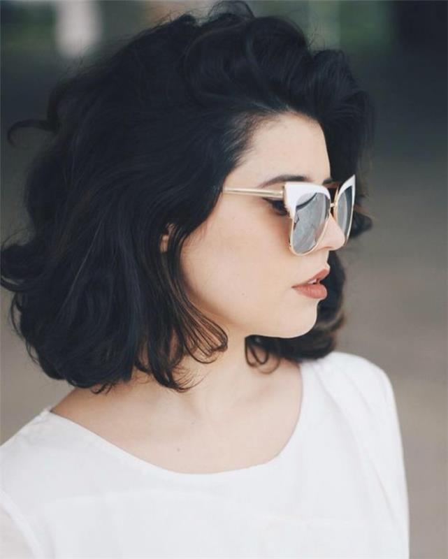 sevimli kısa saç kesimi, kısa hacimli siyah dalgalı saçlı kadın, beyaz üst giyen ve beyaz çerçeveli retro güneş gözlükleri