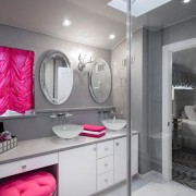 Aparatos llamativos de color rosa brillante sobre un fondo de paredes grises neutrales: un elegante interior de baño