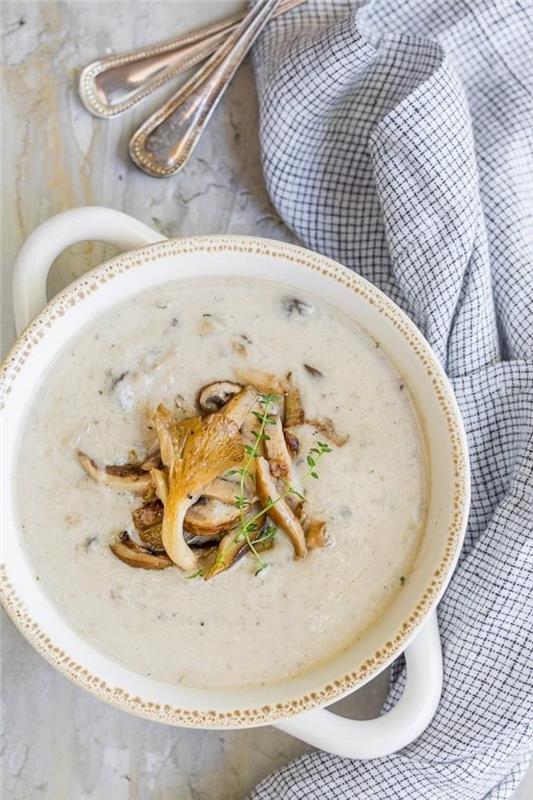 Minestra frullata con funghi, pentola con vellutata di verdure, piatto con cucchiai